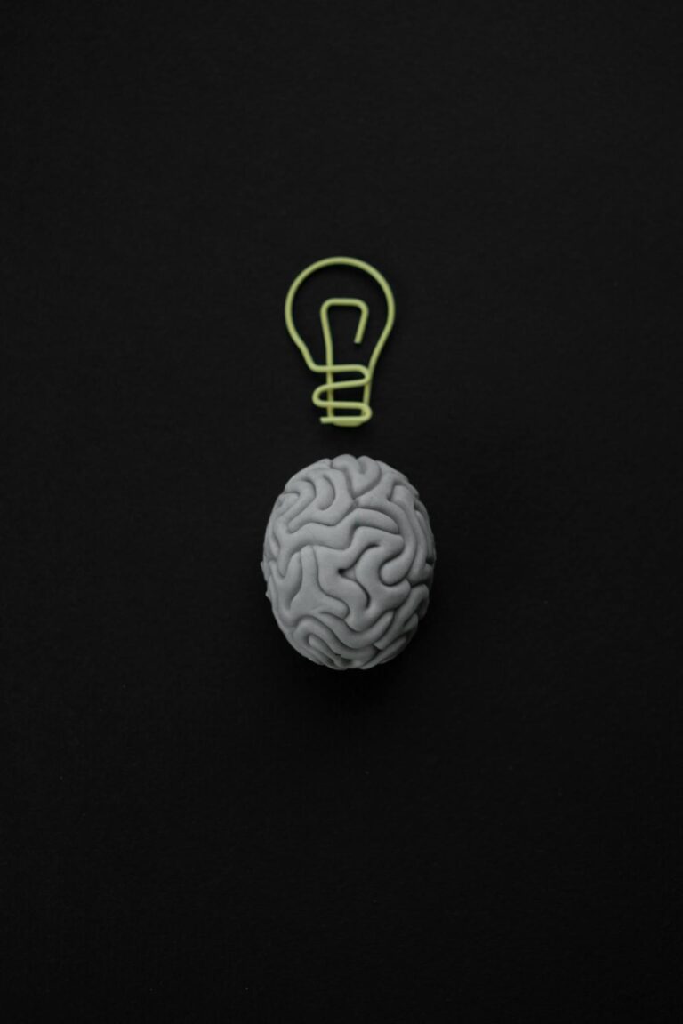 Gray brain with light bulb symbol on black background representing intelligence and creativity.